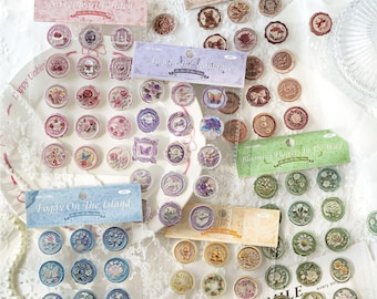 May include: A collection of adhesive wax seal stickers featuring various botanical, floral, and animal motifs in circular and rectangular shapes. The stickers are organized on clear backing sheets with labels including Sweet Heart Garden, Angel Romance, Foggy On The Island, and Blooming Flowers In The Wild.
