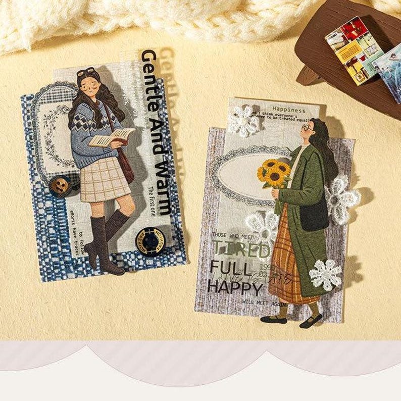 May include: Two rectangular decorative paper cards featuring illustrated figures. The left card shows a person in a blue sweater and plaid skirt reading a book with text reading Gentle And Warm. The right card shows a person in a green coat holding sunflowers with text reading Happiness, Tired, Full, Happy.