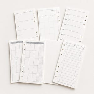 May include: A set of white planner inserts with pre-printed black text and grid lines. The pages feature various layouts including weekly schedules, monthly calendars, and task lists with columns labeled Time, Project, and Done, all with punched holes.