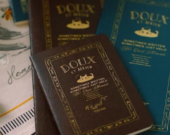 Cuaderno de viaje con diseño de gato, páginas en blanco, cubierta con textura de cuero, tamaños estándar y pasaporte.