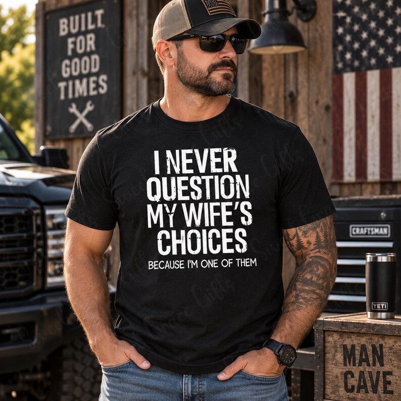 May include: A black short-sleeved t-shirt featuring white distressed text that reads I NEVER QUESTION MY WIFE'S CHOICES BECAUSE I'M ONE OF THEM. The shirt is made of a cotton-style fabric and has a crew neckline with a standard fit for casual wear.