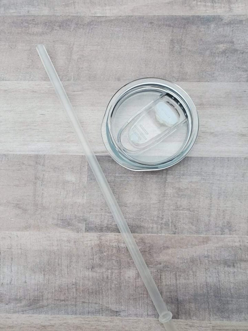 May include: A clear plastic drinking straw with a white lid on top of a stainless steel tumbler.