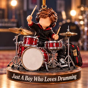 May include: A hanging ornament featuring a brown-haired figure wearing headphones and a black hoodie, playing a red drum set. The circular base is inscribed with the text "Just A Boy Who Loves Drumming" in white lettering against a dark background.