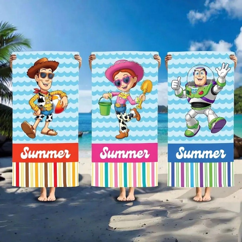 May include: Three beach towels with cartoon characters Woody, Jessie, and Buzz Lightyear. Each towel has a blue wave pattern background and the word "Summer" at the bottom. The towels have colourful striped borders.