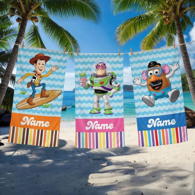 May include: Three beach towels with cartoon characters hanging on a clothesline. The towels feature Woody, Buzz Lightyear, and Mr. Potato Head. Each towel has a colorful striped border and the word "Name" printed on it. The background is a beach scene with palm trees.