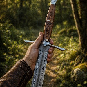 May include: A detailed close-up of a sword with a wooden handle and silver accents. The blade has a unique pattern. The sword is held in a hand, with a leather-clad arm visible. The background is blurred, suggesting an outdoor setting.