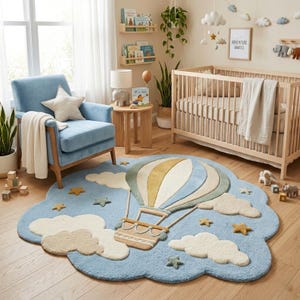 May include: A cloud-shaped area rug featuring a central hot air balloon design in shades of blue, cream, and tan. The rug is decorated with tufted clouds and small stars scattered across a light blue background, creating a textured surface.