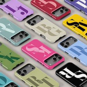 May include: A collection of colorful phone cases with various initial letter designs. The cases are in shades of pink, yellow, green, blue, and purple. Each case features a different set of initials in a contrasting color, creating a personalized and stylish look.