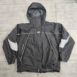 May include: A black Helly Hansen hooded jacket featuring a front zipper closure, long sleeves with light gray panels, and white piping accents. The chest displays the HH logo and the text Helly Tech, with an adjustable drawstring hood.