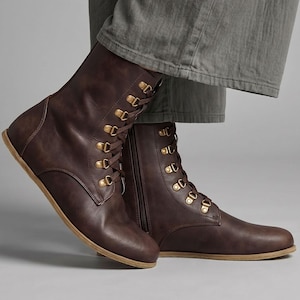 May include: Brown leather boots with gold-colored eyelets and laces. The boots have a side zipper and a flat sole. The boots are worn with gray pants. The Etsy shop name "fentybarefoot.etsy.com" is visible at the bottom of the image.