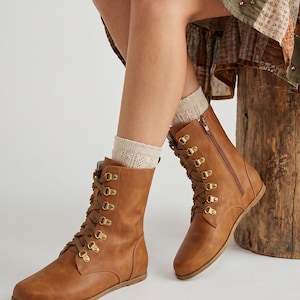 May include: A pair of brown leather lace-up boots with gold-colored eyelets and a side zipper. The boots have a flat sole and are worn with cream-colored socks. The Etsy shop name "fentybarefoot.etsy.com" is visible at the bottom of the image.