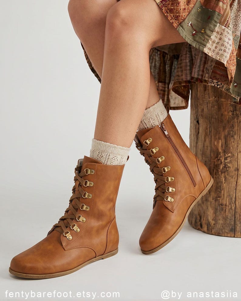 May include: A pair of brown leather lace-up boots with gold-colored eyelets and a side zipper. The boots have a flat sole and are worn with cream-colored socks. The Etsy shop name "fentybarefoot.etsy.com" is visible at the bottom of the image.