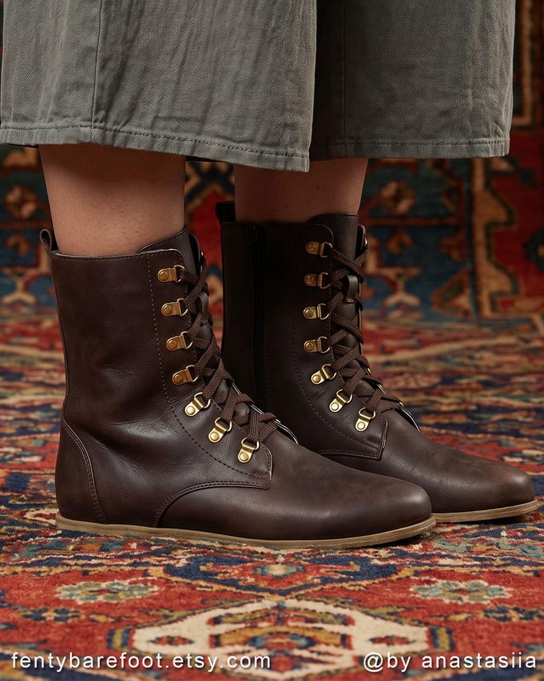 May include: Brown leather boots with brass eyelets and brown laces. The boots have a flat sole and a mid-calf height. The boots are displayed on a patterned rug. The Etsy shop name "fentybarefoot.etsy.com" is visible at the bottom of the image.
