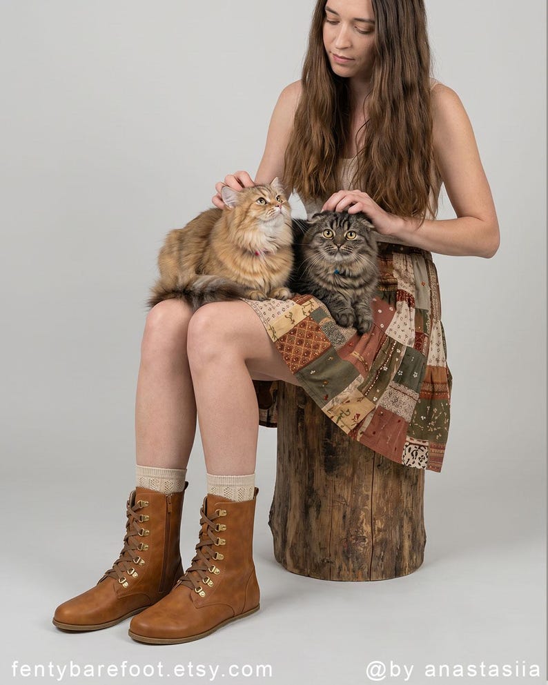 May include: A person sits with two cats, one brown and one gray, on their lap. They wear a patchwork skirt, tan socks, and brown lace-up boots. The boots have gold-colored eyelets. The Etsy shop name "fentybarefoot.etsy.com" is visible.