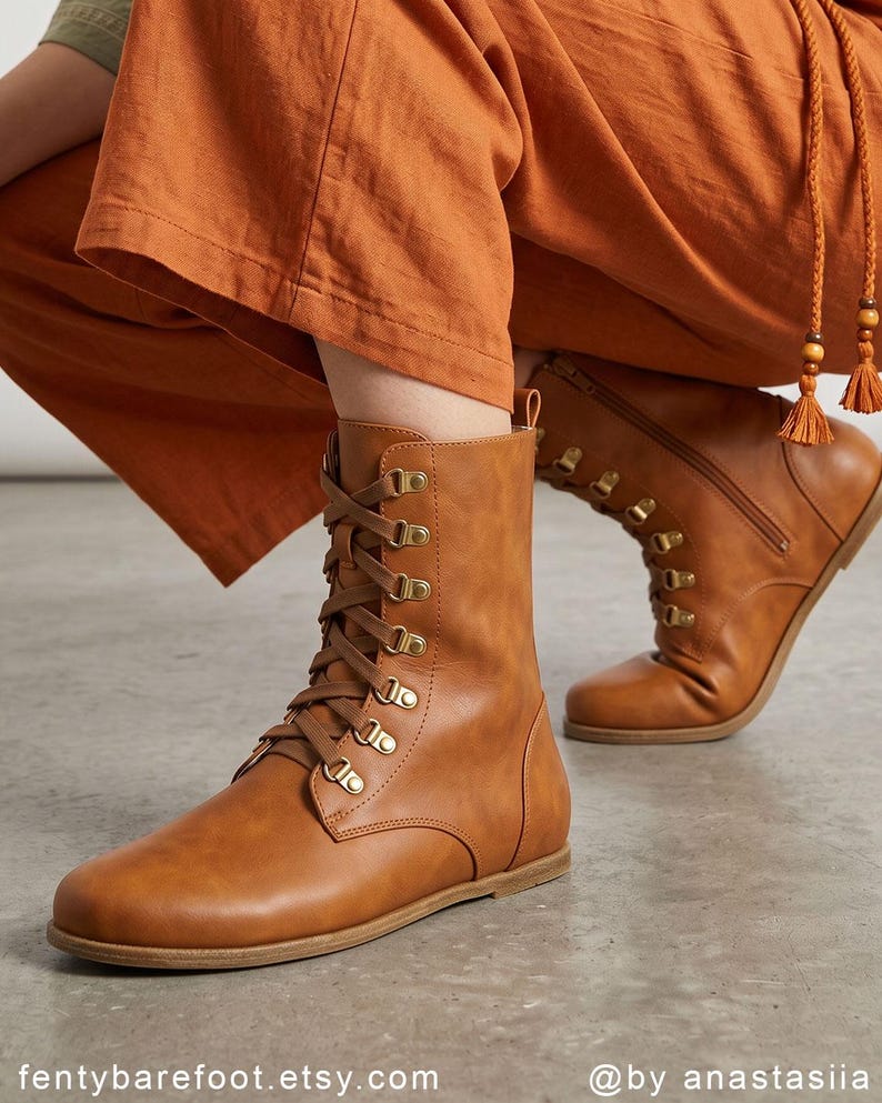 May include: A pair of brown leather lace-up boots with gold-colored eyelets and a side zipper. The boots have a flat sole and are worn with orange pants. The Etsy shop name "fentybarefoot.etsy.com" is visible at the bottom of the image.