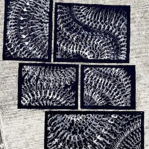 Puede incluir: Cinco parches de tela rectangulares con un estampado abstracto en blanco y negro con patrones repetitivos curvos, esqueléticos o similares a helechos. Cada pieza tiene un borde negro sólido que enmarca el diseño monocromático.