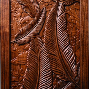May include: A rectangular wooden wall panel featuring a deep relief carving of multiple large, elongated tropical leaves. The dark brown wood grain is visible throughout the intricate design, which includes smaller floral elements and swirling patterns.