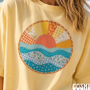 Può includere: Una t-shirt a maniche corte color giallo pallido con una grafica circolare sul petto. Il design raffigura un sole che sorge sopra le onde, realizzato con vari motivi di tessuto in stile patchwork, inclusi stampe floreali, a quadretti e a pois.