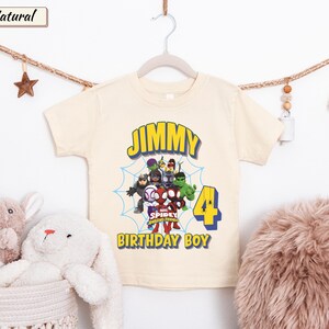 May include: A natural-colored short-sleeve t-shirt featuring a graphic of Marvel Spidey and His Amazing Friends characters, a blue spiderweb, the name JIMMY, the number 4, and the text BIRTHDAY BOY in yellow and blue lettering.