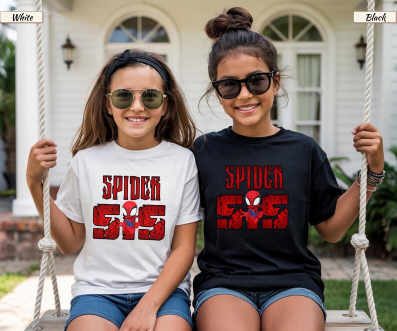 May include: Two girls wearing Spider-Man t-shirts. One shirt is white, the other is black. Both shirts have the words "SPIDER" and "555" in red, with a Spider-Man graphic. The girls are smiling and wearing sunglasses.