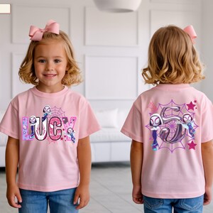 K&ouml;nnte beinhalten: Hellrosa T-Shirt mit dem Namen "LUCY" in einem Comic-Schriftstil, mit Spider-Gwen-Charakteren und einem Spinnennetz-Design. Auf der R&uuml;ckseite des T-Shirts ist eine gro&szlig;e "5" mit Spider-Gwen-Charakteren und Sternen abgebildet.