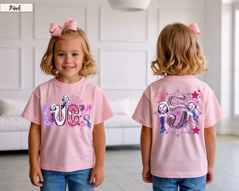 K&ouml;nnte beinhalten: Hellrosa T-Shirt mit dem Namen "LUCY" in einem Comic-Schriftstil, mit Spider-Gwen-Charakteren und einem Spinnennetz-Design. Auf der R&uuml;ckseite des T-Shirts ist eine gro&szlig;e "5" mit Spider-Gwen-Charakteren und Sternen abgebildet.