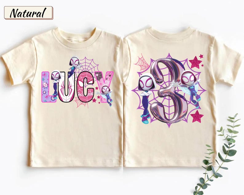 K&ouml;nnte beinhalten: Cremefarbenes T-Shirt mit dem Namen "Lucy" in einer farbenfrohen Comic-Schriftart, mit Spider-Gwen-Charakteren und einem Spinnennetz-Design. Die R&uuml;ckseite zeigt eine gro&szlig;e "3" mit Spider-Gwen-Charakteren und Sternen.