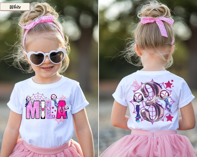 K&ouml;nnte beinhalten: Wei&szlig;es T-Shirt mit dem Namen "MILA" in rosa und lila Buchstaben, mit Spinnennetz- und Superhelden-Grafiken. Auf der R&uuml;ckseite des Shirts befindet sich die Zahl 3 mit Superheldenfiguren und Sternen. Das Kind tr&auml;gt einen rosa T&uuml;llrock und eine Sonnenbrille.