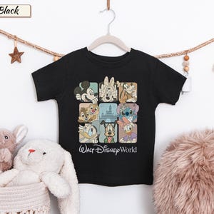 May include: A black short-sleeve t-shirt featuring a grid of nine squares containing illustrations of various Disney characters and a castle. Below the grid, the text Walt Disney World is printed in a white script font on the front of the shirt.