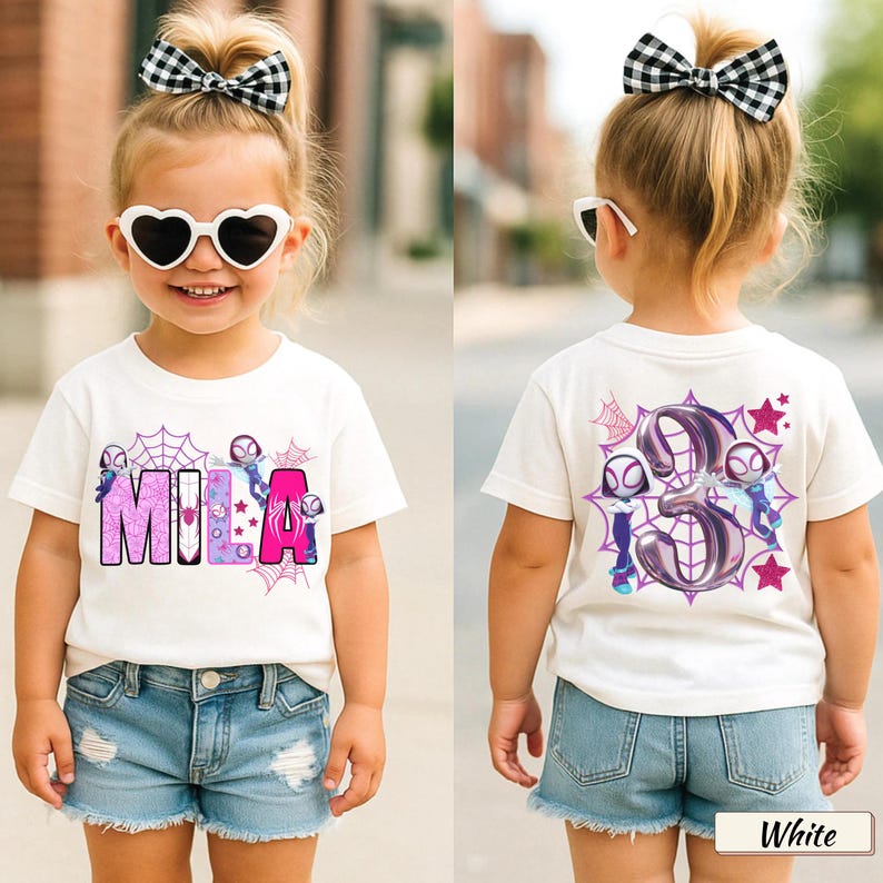 K&ouml;nnte beinhalten: Wei&szlig;es T-Shirt mit dem Namen "MILA" in rosa und lila Buchstaben, mit Cartoon-Figuren und Spinnennetzen. Auf der R&uuml;ckseite des Shirts ist die Zahl "3" mit Cartoon-Figuren, Spinnennetzen und Sternen abgebildet. Das Kind tr&auml;gt Jeansshorts und herzf&ouml;rmige Sonnenbrillen.