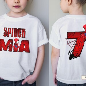 May include: White t-shirt featuring a Spider-Man graphic. The front displays "SPIDER MIA" in red, distressed lettering with a Spider-Man figure. The back shows a red number 7 with a spider web and Spider-Man.