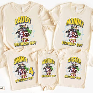 May include: A collection of five cream-colored t-shirts and one bodysuit featuring a graphic of Spidey and His Amazing Friends characters over a blue spiderweb. The shirts include text such as DADDY, MOMMY, JIMMY, BROTHER, SISTER, and BIRTHDAY BOY.