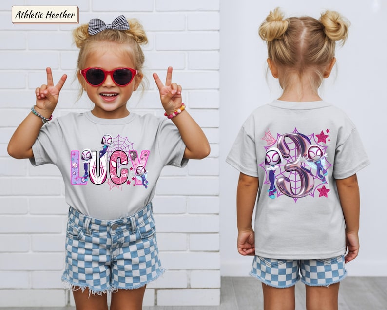 K&ouml;nnte beinhalten: Hellgraues T-Shirt mit dem Namen "LUCY" in rosa und blauen Buchstaben, mit einem Spider-Gwen-Thema. Auf der R&uuml;ckseite des Shirts ist eine gro&szlig;e "3" mit Spider-Gwen-Charakteren und Sternen abgebildet. Getragen von einem jungen M&auml;dchen.