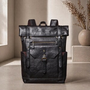 Può includere: Zaino in pelle nera con chiusura arrotolabile, tasca frontale e tasche laterali. Lo zaino è dotato di spallacci regolabili, maniglia superiore e hardware color ottone. La borsa ha uno stile classico e vintage.