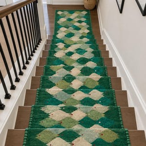 May include: A long stair runner rug featuring a repeating diamond pattern in shades of emerald green, light green, and cream. The runner has a textured surface and is finished with a decorative beaded edge along both sides of the length.