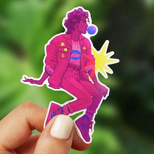 May include: A sticker featuring a stylized illustration of a person in a pink outfit blowing a bubble. The person is wearing a pink jacket, pants, and sneakers. A yellow starburst is behind the person.