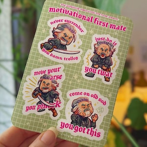May include: A sticker sheet featuring four cartoon illustrations of a stern-looking character with motivational phrases. The phrases include "never surrender," "just do it," "move your arse," and "come on old sod."