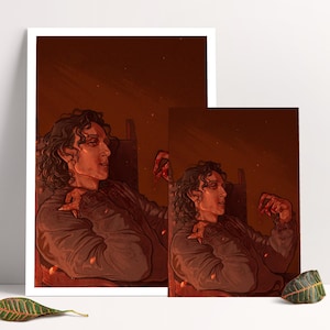 Puede incluir: Dos impresiones artísticas que representan a una persona con cabello rizado, sentada en una silla, con una paleta de colores cálida, rojiza y marrón. Las impresiones se exhiben sobre una superficie blanca, con una hoja en primer plano.