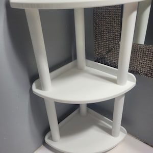 Peut inclure: Étagère d'angle blanche à trois niveaux. L'étagère a une forme triangulaire avec des bords arrondis et est soutenue par des pieds cylindriques. Design simple et moderne, adapté au rangement dans la salle de bain ou la cuisine.
