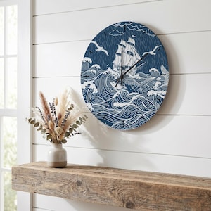 Puede incluir: Un reloj de pared redondo con fondo azul oscuro y una ilustración de líneas blancas de un velero navegando entre olas agitadas, lluvia y nubes. El reloj tiene manecillas negras para las horas y los minutos y marcas negras.