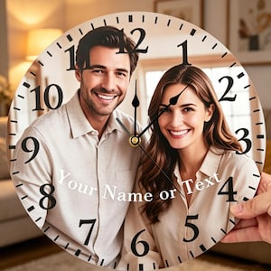 May include: A round wall clock featuring a smiling couple. The clock face displays black numerals and hands against a background of the couple's photo. The text "Your Name or Text" is printed on the clock face.