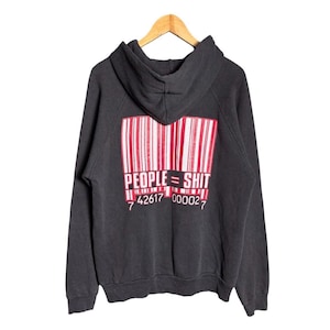 Puede incluir: Una sudadera con capucha de color gris carbón que presenta un gráfico grande en la parte posterior. El diseño muestra un patrón de código de barras rojo y blanco con el texto "PEOPLE = SHIT" en blanco y la secuencia numérica 7 42617 00002 7.