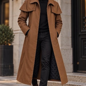May include: A long, tan trench coat featuring a wide cape-style collar, long sleeves, and a black quilted interior lining. The coat is worn over a black turtleneck sweater and black trousers, paired with brown leather ankle boots and sunglasses.