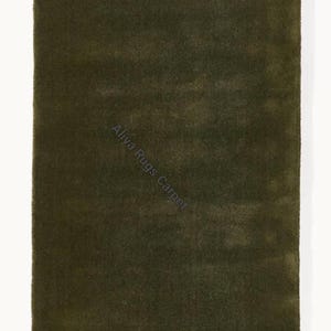 May include: A rectangular, olive green rug with a soft, textured surface. The rug has a solid color and is displayed against a white background. The text "Aliya Rugs Carpet" is visible on the rug.