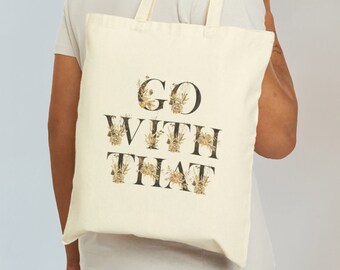 May include: A white canvas tote bag with the text "GO WITH THAT" printed in black. The letters are decorated with a floral pattern in gold and brown.