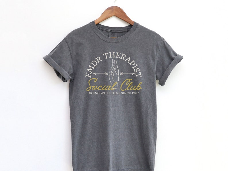 May include: Gray t-shirt with a white graphic design that says "EMDR Therapist Social Club Going With That Since 1987".