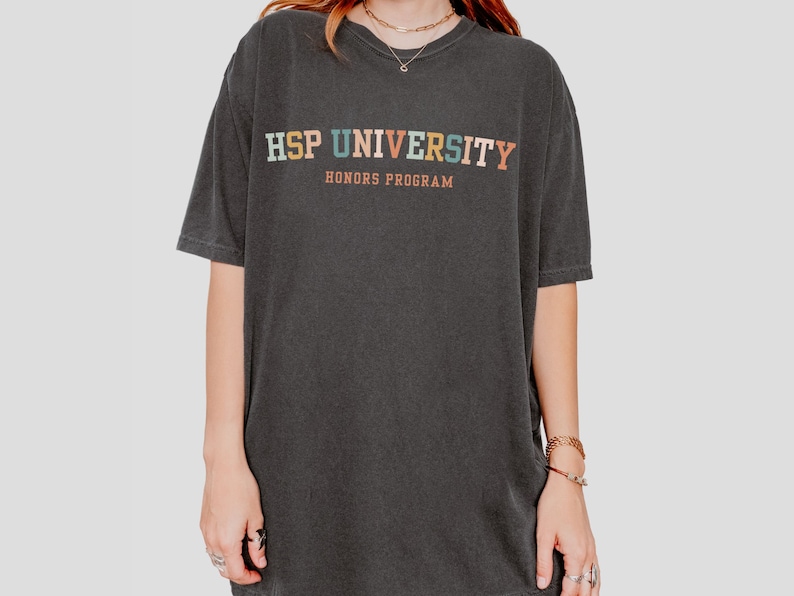 K&ouml;nnte beinhalten: Ein schwarzes T-Shirt mit dem Text "HSP UNIVERSITY HONORS PROGRAM" in bunten Buchstaben.