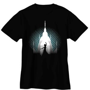 May include: Black t-shirt featuring a white silhouette of a building with a figure in front, set against a patterned blue and white background. The design evokes a sense of wonder and fantasy, suitable for casual wear.