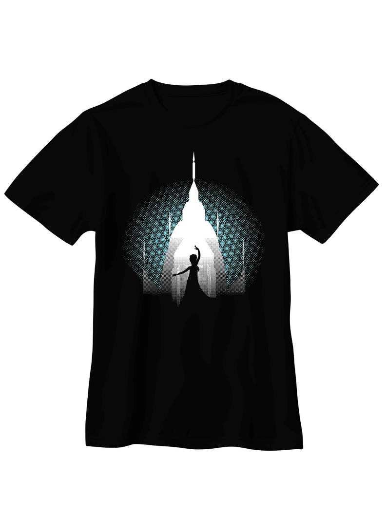 May include: Black t-shirt featuring a white silhouette of a building with a figure in front, set against a patterned blue and white background. The design evokes a sense of wonder and fantasy, suitable for casual wear.