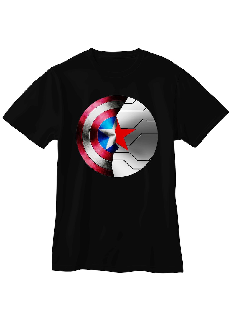 May include: Black t-shirt featuring a graphic design of Captain America's shield and the Winter Soldier's arm. The shield is red, white, and blue with a star, while the arm is metallic silver. The design is centered on the front of the shirt.